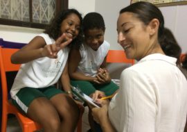 Sally, who volunteered to teach English in Brazil with EduMais, makes the classroom rules with two students, one making a peace sign