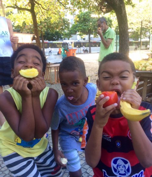 EduMais after-school program boys make funny faces while holding up various different fruits