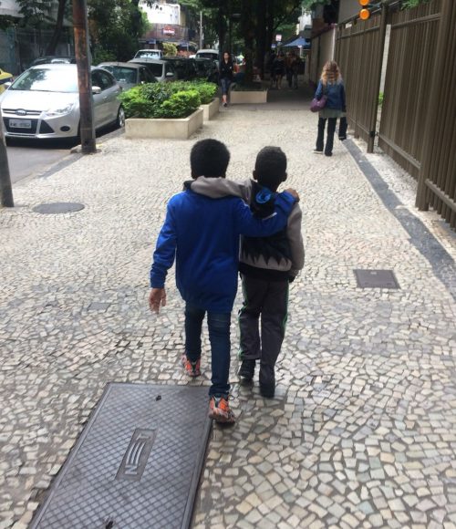 EduMais after-school program students Andre and Renee walk down a street in Ipanema with their arms around each other