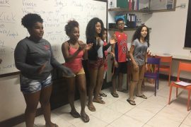 EduMais Community English class play a game of Simon Says at the front of the classroom