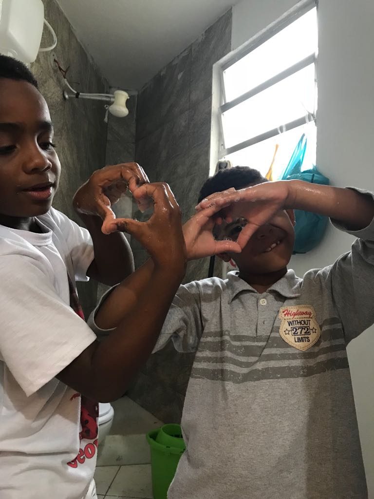 EduMais after-school program students Andre and Romulo form heart shapes with their hands