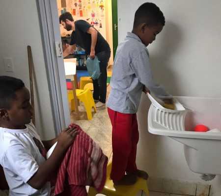 EduMais after-school students wash up their plates with Ed, a volunteer in Rio de Janeiro with EduMais