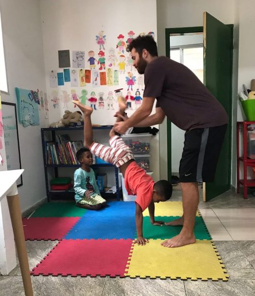 EduMais after-school program student Romulo attempts a handstand with volunteer Ed holding his legs in support