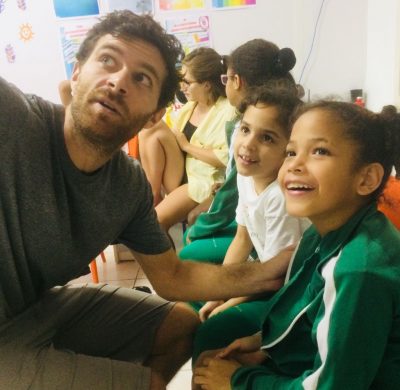 Volunteer English teacher Ed helps smiling EduMais girls with their English in the classroom