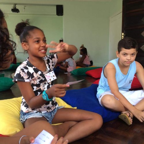 A girl student at EduMais's English Summer Camp 2019 holds up three fingers as she begins a game of 2 truths and a lie