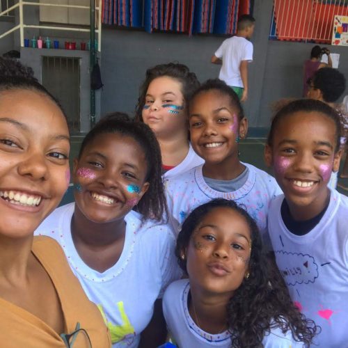 5 girls at EduMais's Summer Camp 2019 and volunteer Thais take a selfie with their cheeks covered in multicoloured glitter