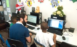 EduMais Web Design Program volunteer Felipe teaches two boys how to build their websites